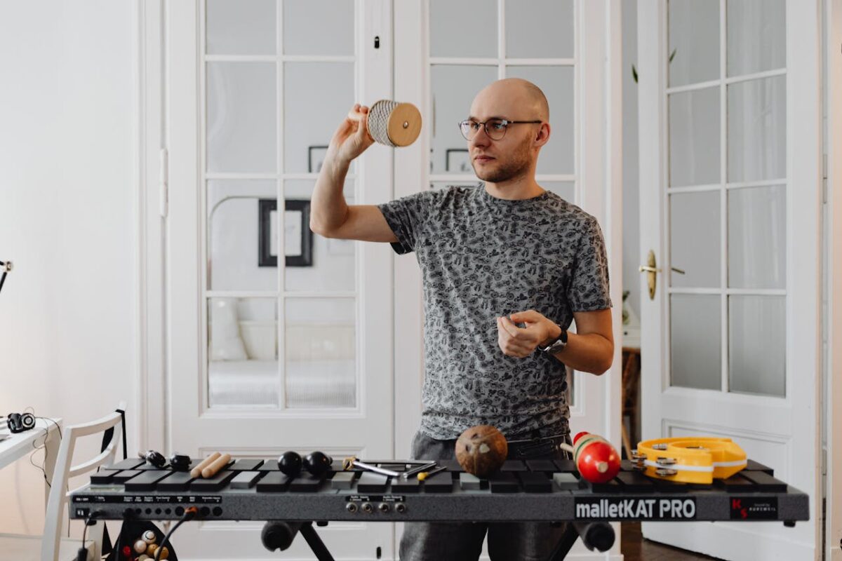 Musician holding percussion instrument while standing behind a malletKAT in a bright room.