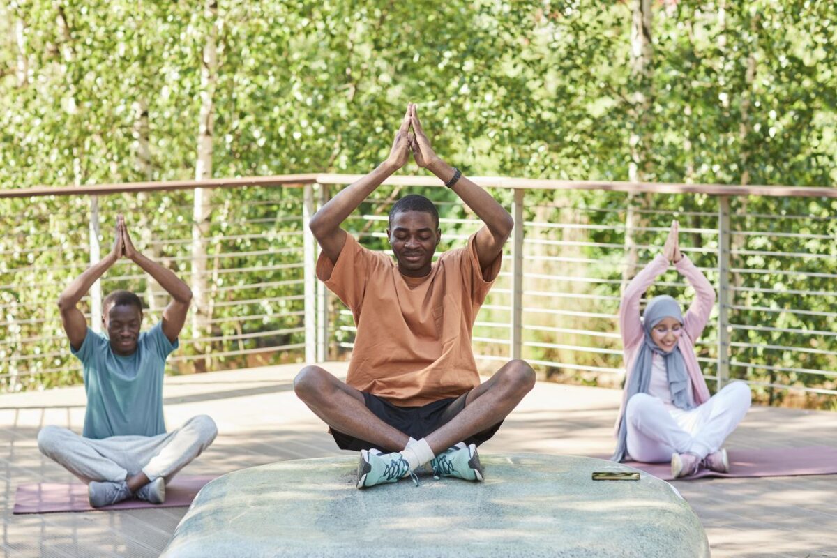 A diverse group of people meditating outdoors in a serene setting, promoting wellness and relaxation.